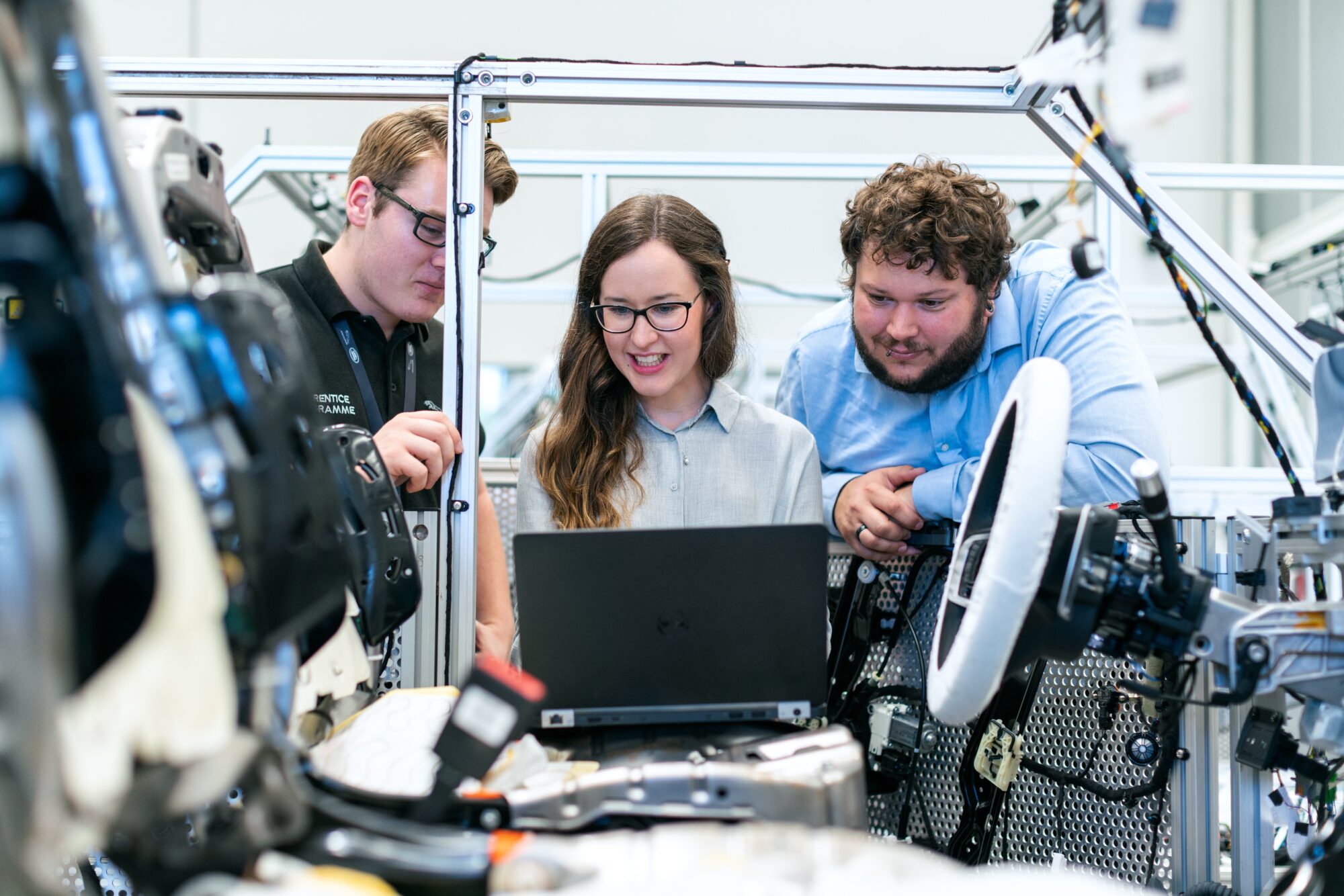 Three people reviewing technical training material on a laptop
